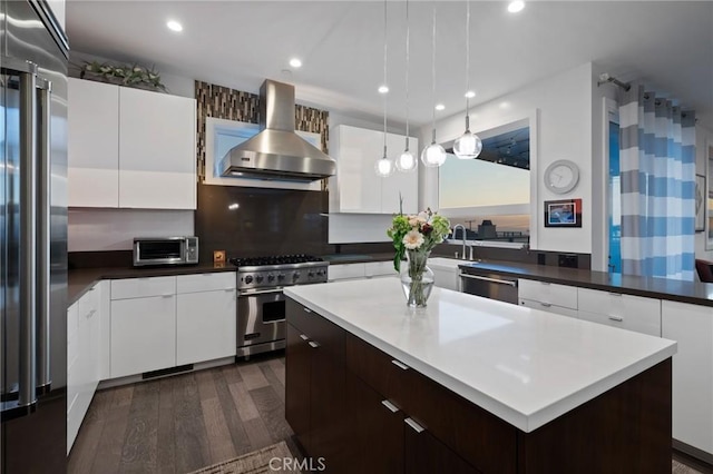 kitchen with wall chimney exhaust hood, high quality appliances, white cabinets, dark wood-style flooring, and recessed lighting