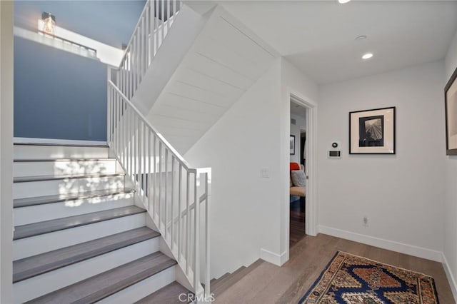 stairway featuring recessed lighting, baseboards, and wood finished floors
