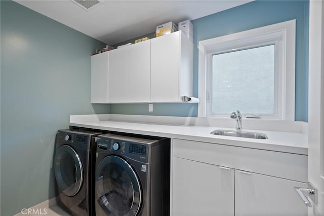 clothes washing area featuring cabinet space, visible vents, washer and dryer, and a sink