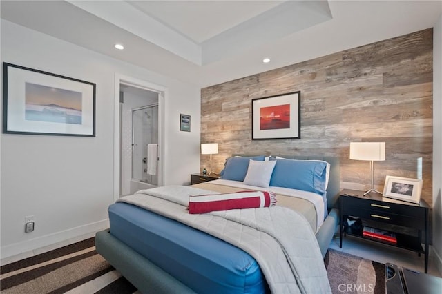 bedroom featuring baseboards, a raised ceiling, an accent wall, wooden walls, and recessed lighting
