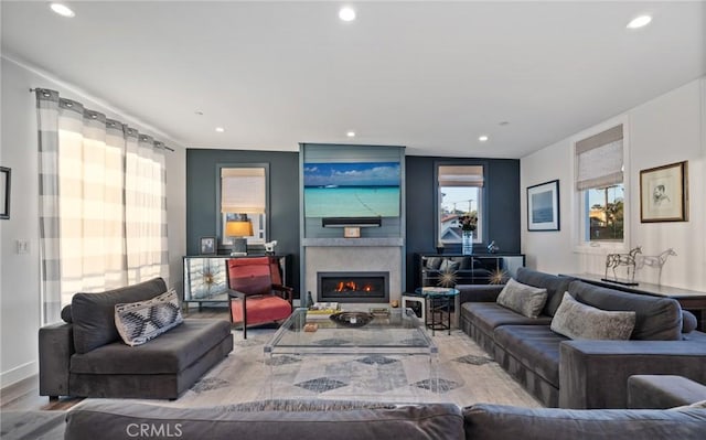 living area with wood finished floors, a lit fireplace, and recessed lighting
