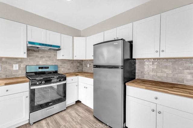 kitchen with under cabinet range hood, wooden counters, white cabinetry, decorative backsplash, and stainless steel appliances
