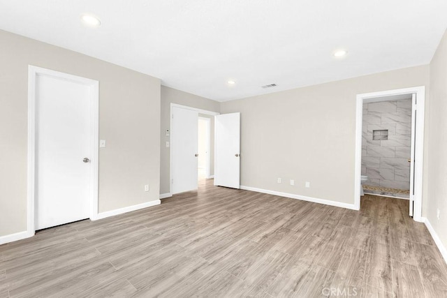unfurnished bedroom with light wood finished floors, visible vents, baseboards, ensuite bath, and recessed lighting
