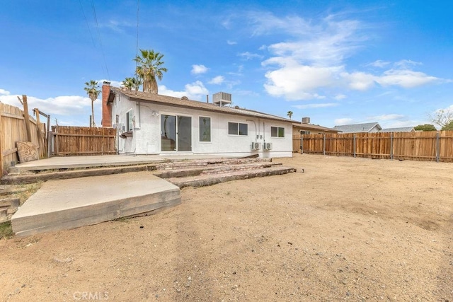 rear view of property with stucco siding, a fenced backyard, and a patio