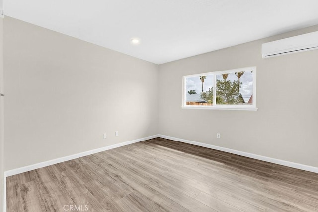 spare room with recessed lighting, an AC wall unit, baseboards, and wood finished floors