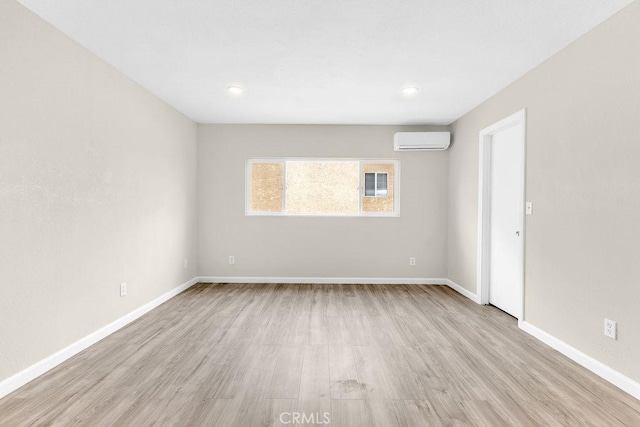 empty room featuring wood finished floors, baseboards, a wall mounted AC, and recessed lighting