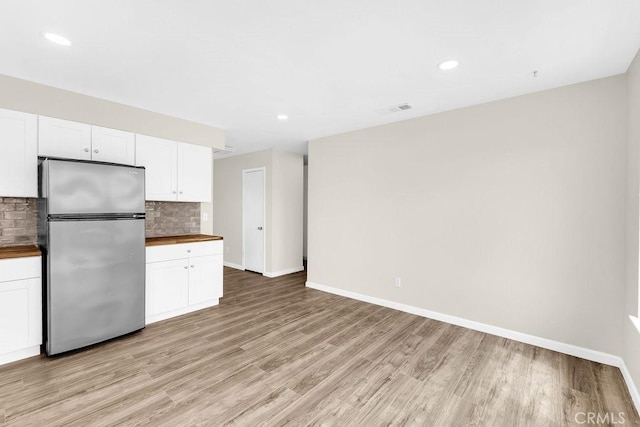 kitchen featuring wood counters, freestanding refrigerator, light wood-style flooring, decorative backsplash, and white cabinets