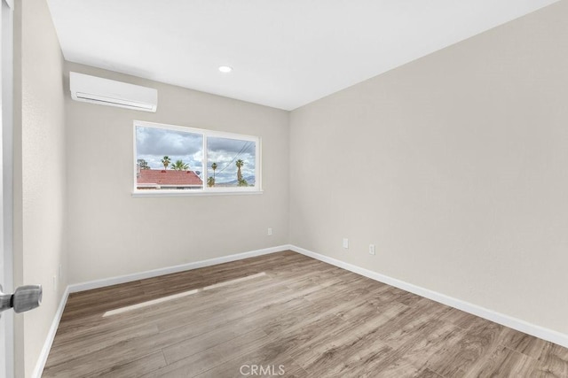 unfurnished room featuring recessed lighting, baseboards, a wall unit AC, and wood finished floors