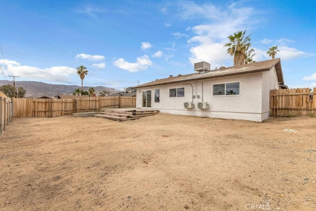 rear view of property featuring a mountain view, stucco siding, and a fenced backyard