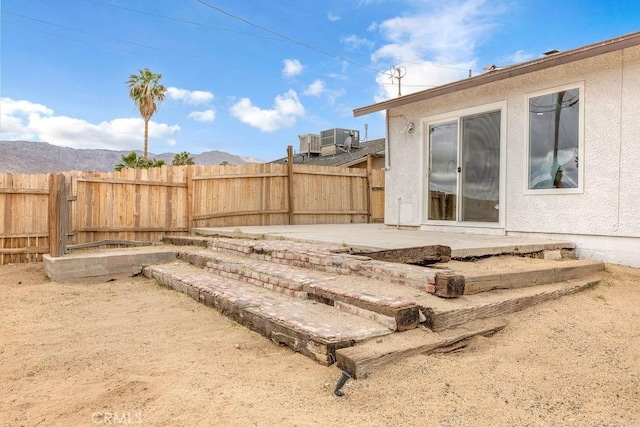 view of yard with a fenced backyard, a patio, central air condition unit, and a mountain view
