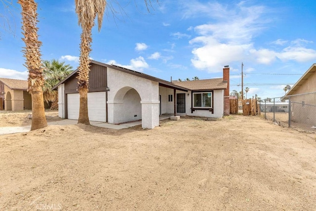 single story home with stucco siding, a chimney, and fence
