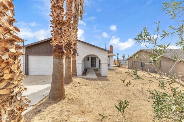 view of front of home featuring driveway, stucco siding, and fence