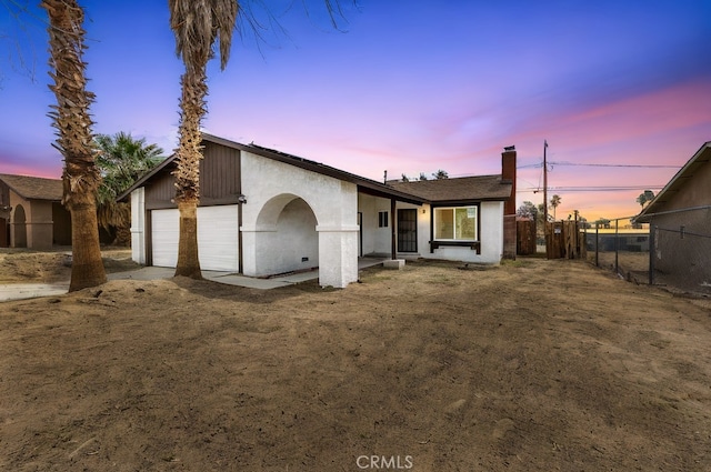 ranch-style house with stucco siding, a chimney, and fence