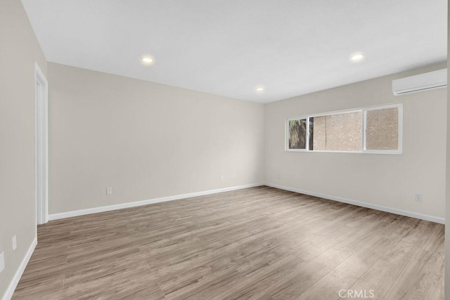 spare room featuring a wall mounted air conditioner, wood finished floors, baseboards, and recessed lighting