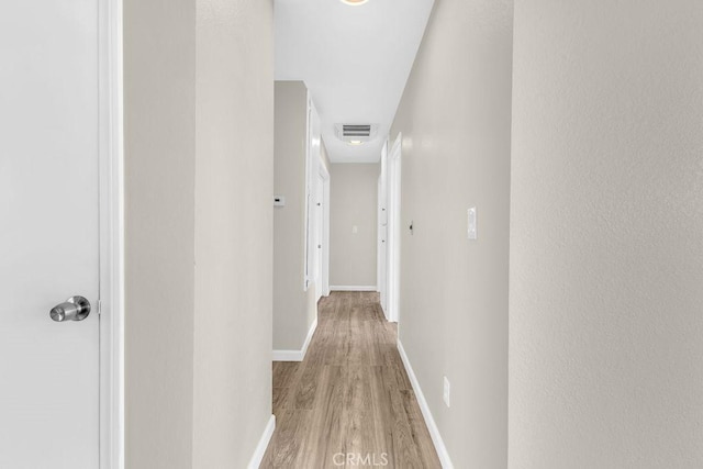 hall with baseboards, light wood-type flooring, and visible vents