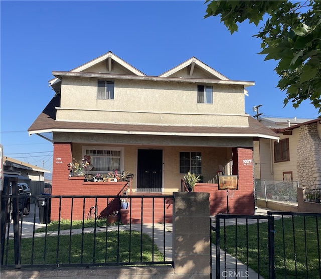 view of front of property featuring a porch, stucco siding, brick siding, and a fenced front yard
