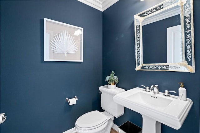 half bathroom with toilet, baseboards, ornamental molding, and a sink
