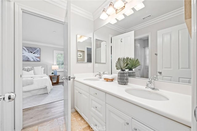 ensuite bathroom featuring a sink, double vanity, ornamental molding, and visible vents