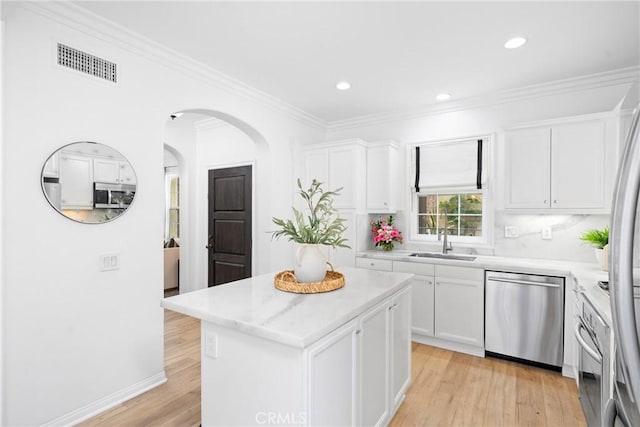 kitchen featuring a sink, stainless steel appliances, white cabinets, visible vents, and arched walkways