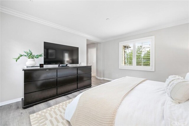 bedroom featuring ornamental molding, baseboards, and light wood-style floors