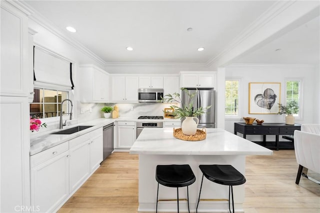 kitchen with a sink, white cabinetry, a kitchen breakfast bar, a kitchen island, and stainless steel appliances