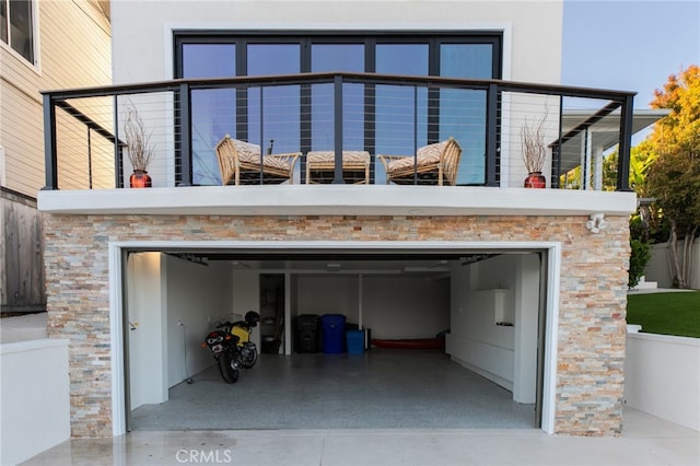1624 Malden St, San Diego, CA 92109 - rear view of property with driveway, stone siding, stucco siding, a balcony, and an attached garage