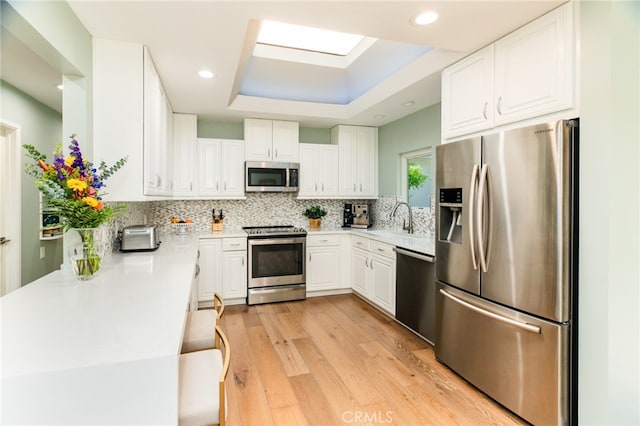 1624 Malden St, San Diego, CA 92109 - kitchen with appliances with stainless steel finishes, a sink, light wood finished floors, white cabinetry, and tasteful backsplash