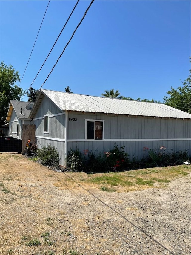 view of property exterior with metal roof and fence