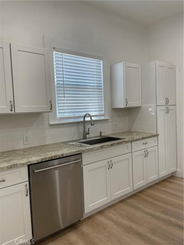 kitchen featuring dishwasher, white cabinetry, decorative backsplash, and a sink