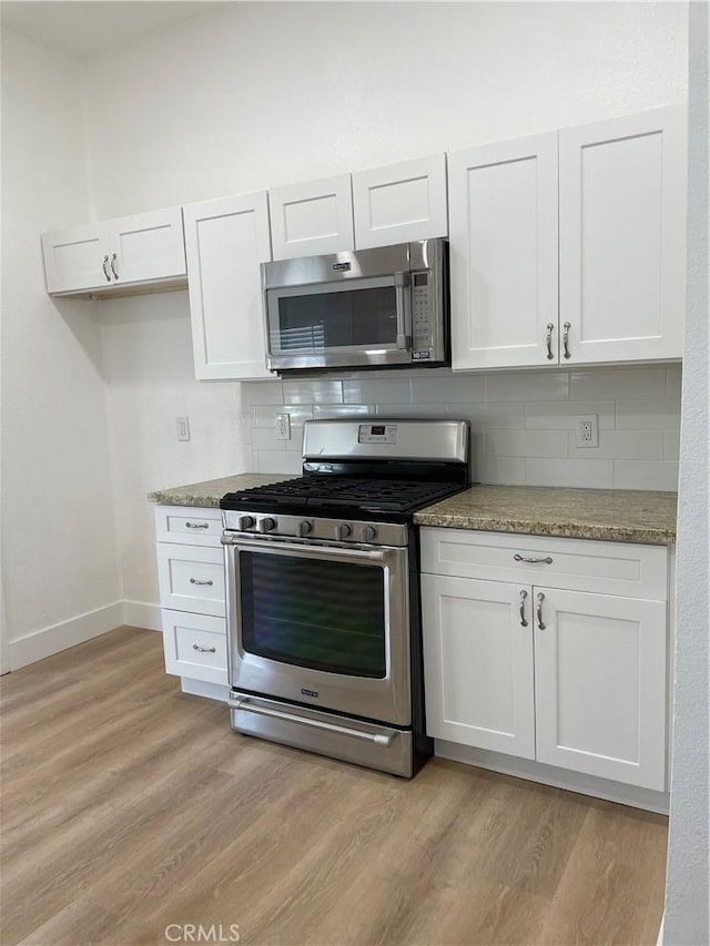 kitchen with stainless steel appliances, decorative backsplash, and white cabinets