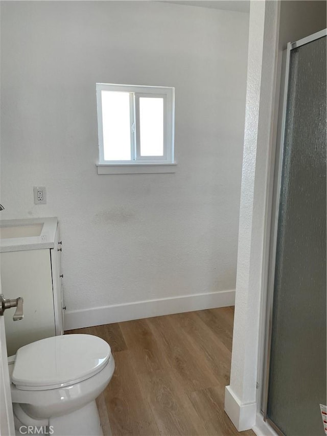 full bath featuring a stall shower, baseboards, toilet, vanity, and wood finished floors