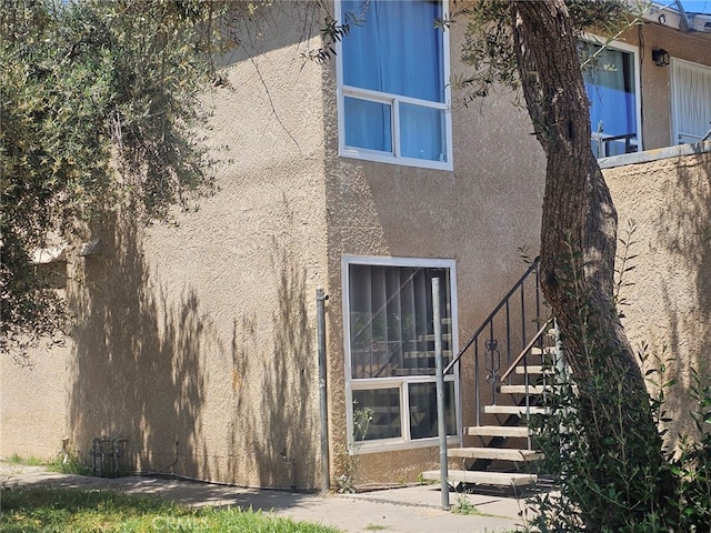back of house featuring stucco siding and stairs