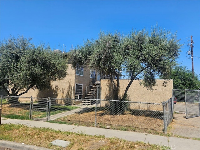 view of front of property with stairs, stucco siding, and a fenced front yard