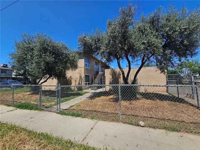 view of front of property featuring stairway, stucco siding, a fenced front yard, and a gate