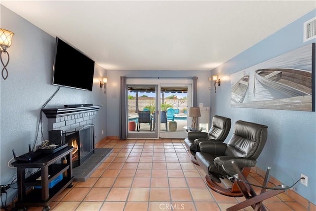 sitting room with a fireplace, light tile patterned flooring, and baseboards