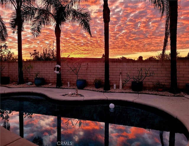 pool at dusk featuring fence