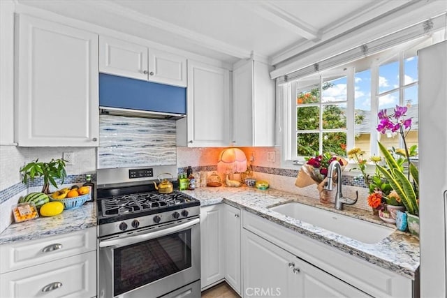 kitchen with white cabinets, backsplash, stainless steel gas range oven, and a sink