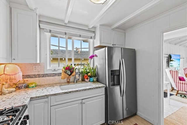 kitchen featuring a sink, appliances with stainless steel finishes, white cabinetry, beamed ceiling, and light wood-style floors