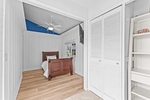 bedroom with a closet, vaulted ceiling, light wood-style flooring, and ceiling fan