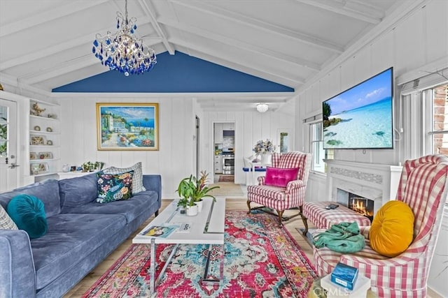 living area with wood finished floors, lofted ceiling with beams, a healthy amount of sunlight, and a glass covered fireplace