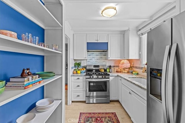 kitchen featuring stainless steel appliances, light stone counters, light wood finished floors, decorative backsplash, and white cabinets
