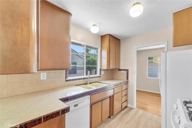 kitchen with white appliances, a sink, tile countertops, decorative backsplash, and a textured ceiling
