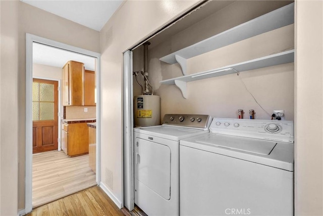 laundry area featuring electric water heater, light wood-type flooring, and washer and dryer