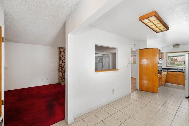 6552 Mallard St, San Diego, CA 92114 - kitchen featuring freestanding refrigerator, a textured ceiling, dark countertops, light tile patterned floors, and brown cabinetry