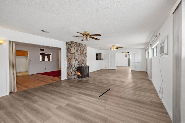 6552 Mallard St, San Diego, CA 92114 - unfurnished living room with a textured ceiling, ceiling fan, light wood-type flooring, a stone fireplace, and a wall unit AC
