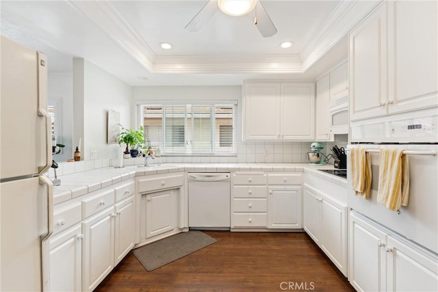kitchen featuring white appliances, tile countertops, crown molding, a ceiling fan, and a tray ceiling