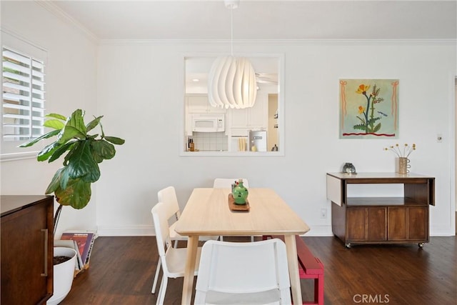 dining space featuring baseboards, crown molding, and wood finished floors