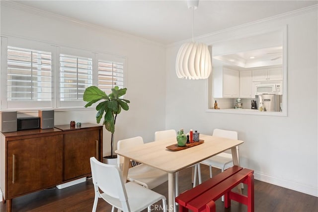 dining room featuring crown molding, baseboards, and dark wood finished floors