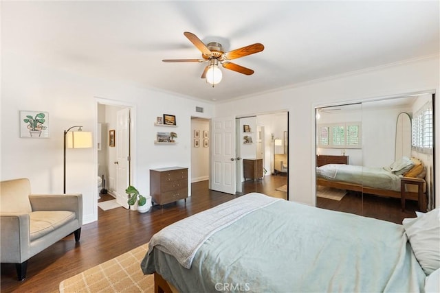 bedroom featuring crown molding, dark wood finished floors, baseboards, and multiple closets