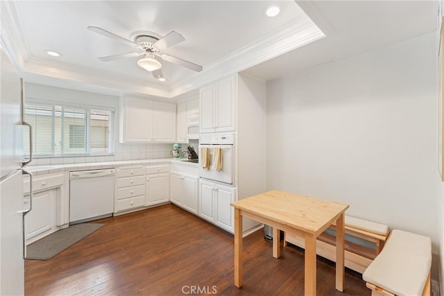 kitchen with a tray ceiling, crown molding, white cabinetry, and white appliances